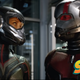 The Wasp and Ant-Man, in their respective armors, stare at each other while standing in a lab.